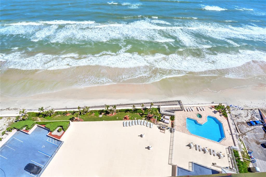 An aerial view shows a beachside resort with a swimming pool, parking lot, and ocean — 1900 N ATLANTIC AVENUE UNIT 1603, DAYTONA BEACH, FL