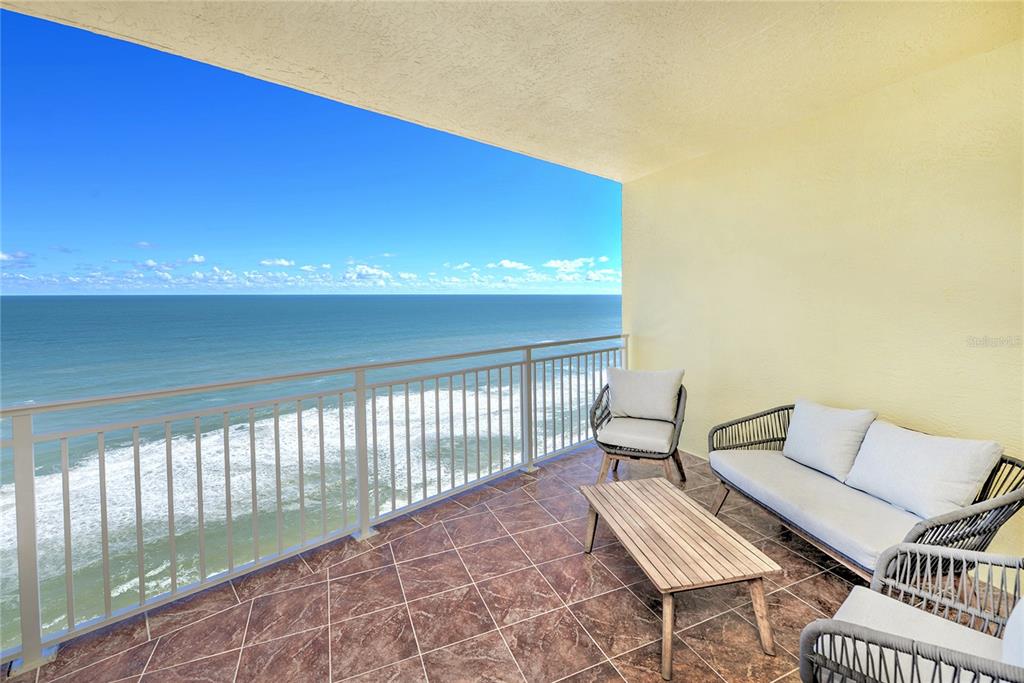 A balcony with tiled flooring, patio furniture, and a view of the ocean — 1900 N ATLANTIC AVENUE UNIT 1603, DAYTONA BEACH, FL