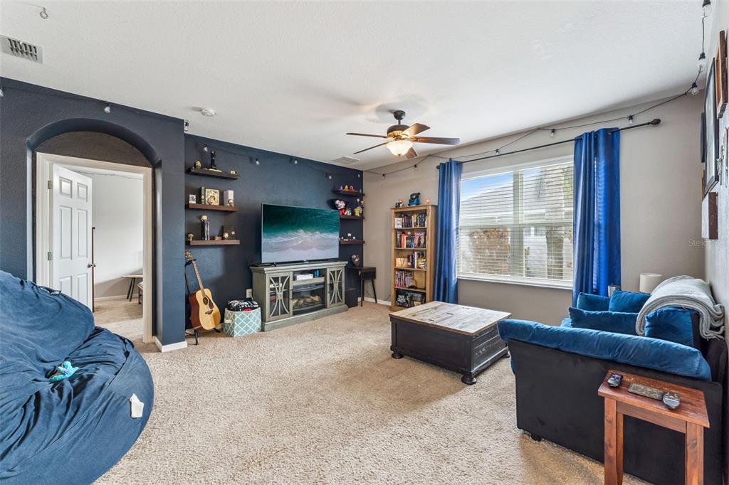 A living room features a dark blue accent wall, a television, shelving, and blue furniture — 5617 YEARLING DRIVE, TITUSVILLE, FL