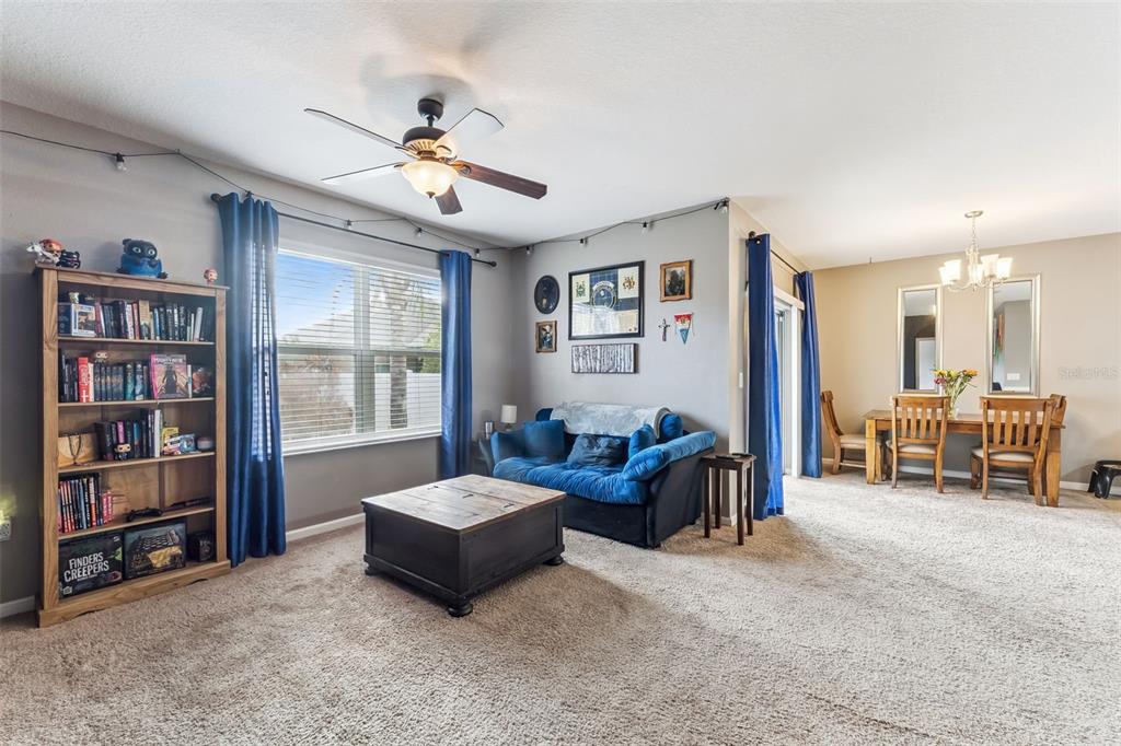 A living room with a blue sofa, wooden coffee table, bookshelf, and adjacent dining area — 5617 YEARLING DRIVE, TITUSVILLE, FL