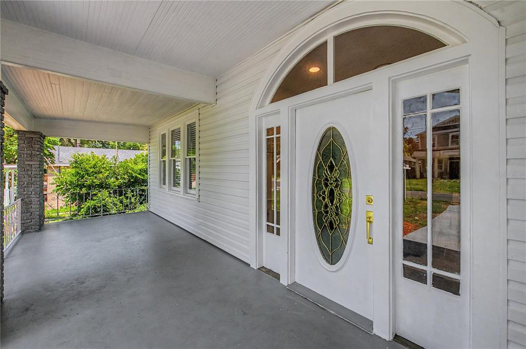 A covered porch features white siding, a gray floor, and a white front door with sidelights — 1920 E PARIS STREET, TAMPA, FL