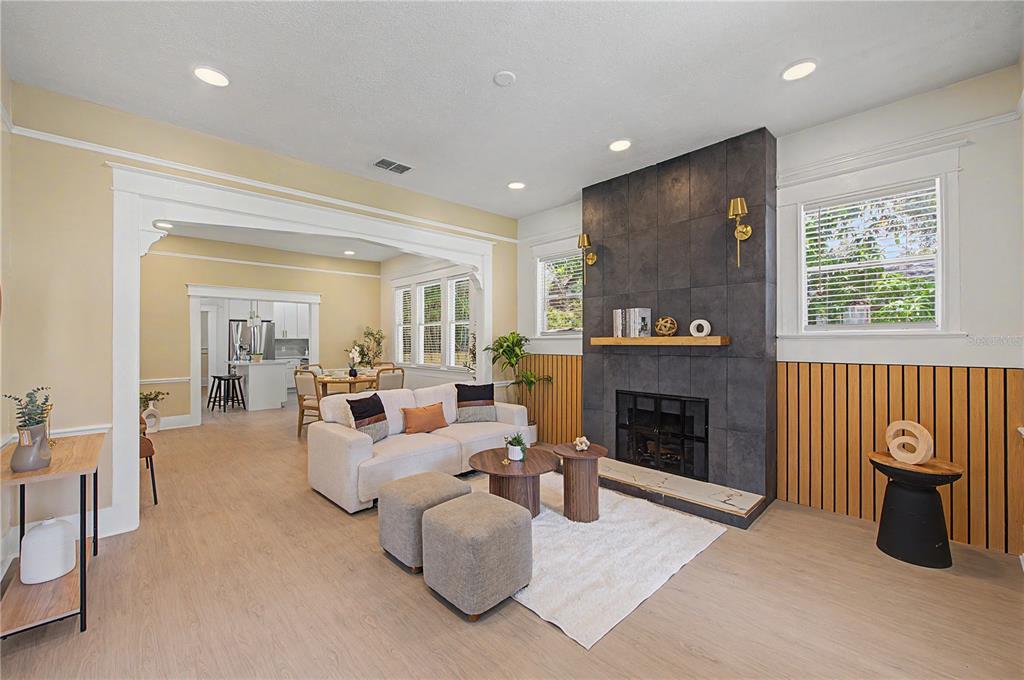 A living room features a dark tiled fireplace, wood slat wall paneling, and light flooring — 1920 E PARIS STREET, TAMPA, FL