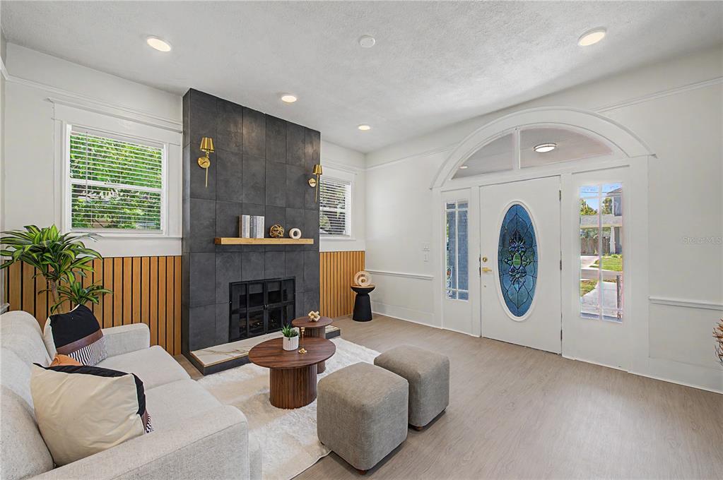 A living room features a dark tiled fireplace, wood slat wall paneling, and a front door — 1920 E PARIS STREET, TAMPA, FL