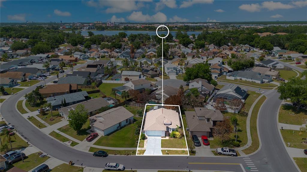 An aerial view shows a single-story house with a light-colored roof and a driveway — 4805 KINGSTON CIR, KISSIMMEE, FL