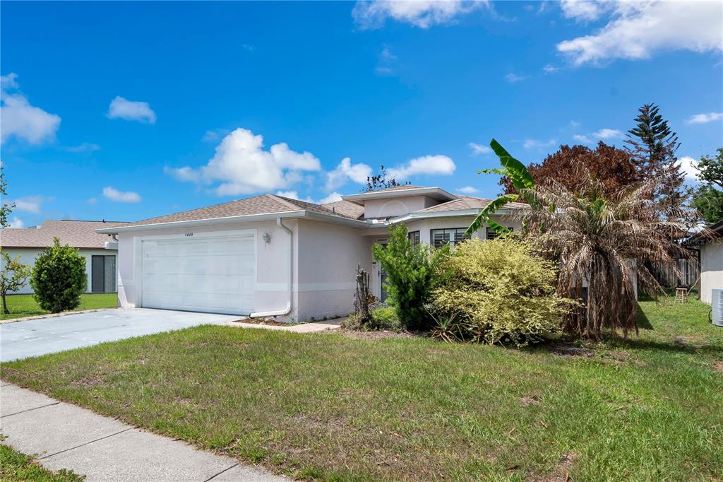 A single-story house with a white garage, light-colored exterior, and a front yard with landscaping — 4805 KINGSTON CIR, KISSIMMEE, FL