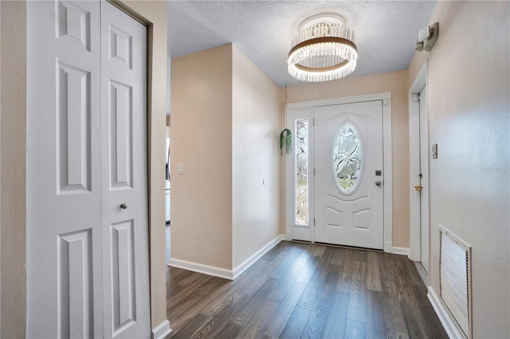 An entryway features wood-look flooring, a white front door with glass, and a crystal chandelier — 4805 KINGSTON CIR, KISSIMMEE, FL