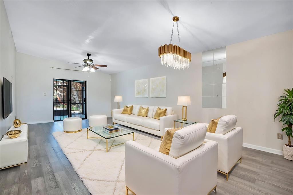 A bright living room features white furniture, a glass coffee table, and a gold chandelier — 4805 KINGSTON CIR, KISSIMMEE, FL