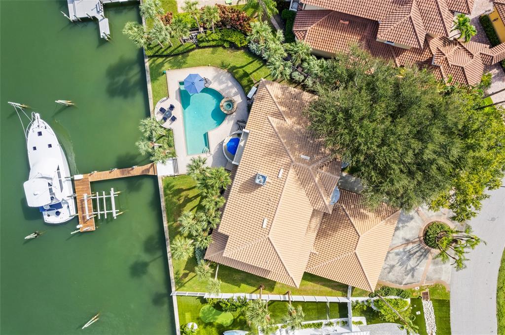 An aerial view shows a waterfront house with a pool, dock, and a large boat — 833 PONCE DE LEON DRIVE, TIERRA VERDE, FL