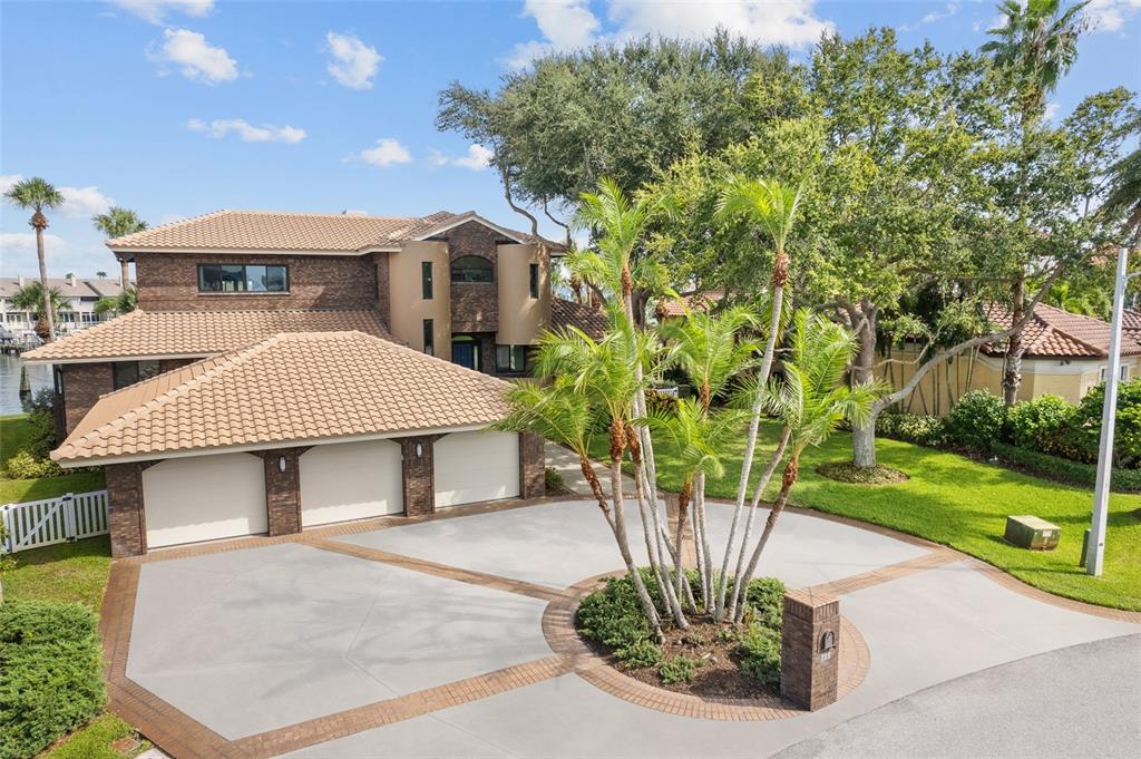 A two-story brick house features a three-car garage and a circular driveway with palm trees — 833 PONCE DE LEON DRIVE, TIERRA VERDE, FL