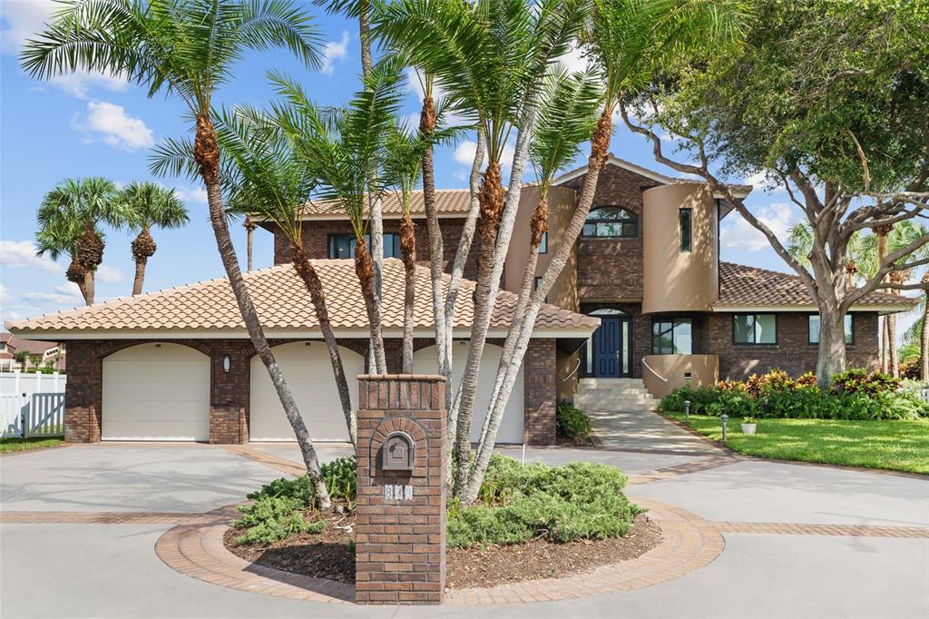 A two-story brick house features a three-car garage, a circular driveway, and palm trees — 833 PONCE DE LEON DRIVE, TIERRA VERDE, FL