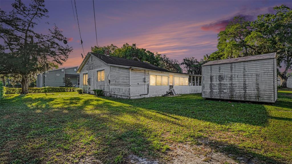 A white wooden house with a detached shed sits on a grassy lot at sunset — 514 SW 2ND AVENUE, OCALA, FL