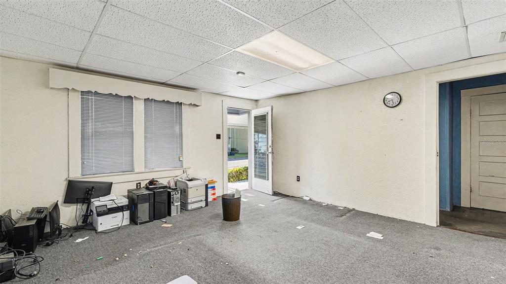 An office room with gray carpet, a drop ceiling, a window, and an open door — 514 SW 2ND AVENUE, OCALA, FL