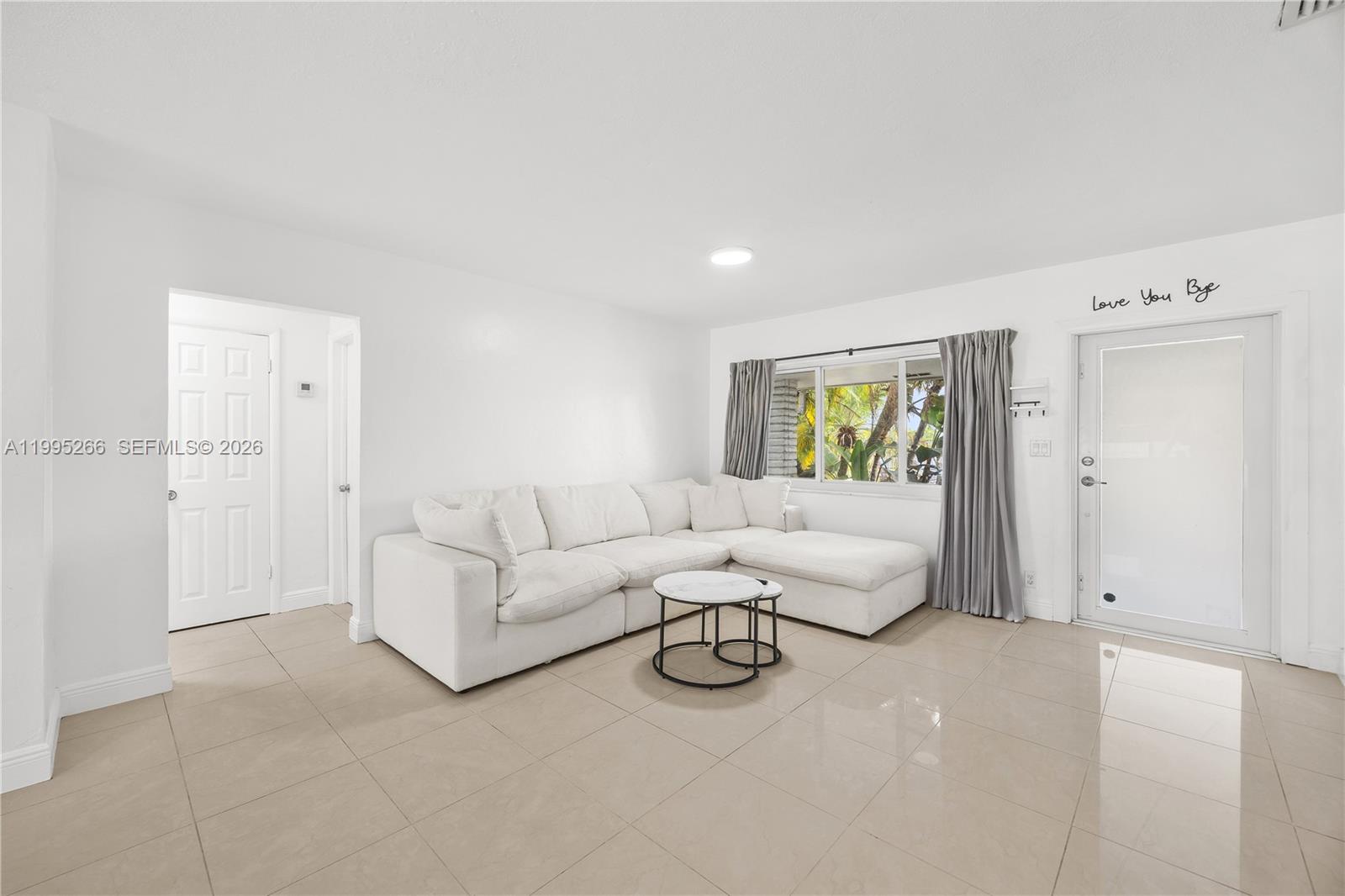 A living room features white walls, tile flooring, a white sectional sofa, and a glass door — 1435 Johnson St, Hollywood FL 33020, HOLLYWOOD, FL