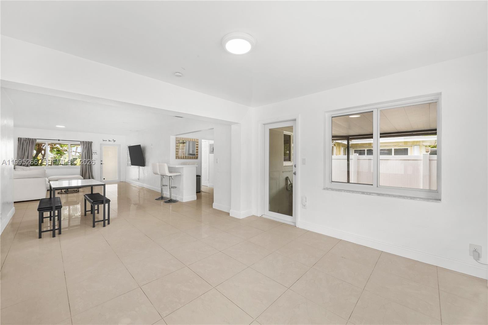 An open-concept living and dining area features white walls, tile flooring, and a breakfast bar — 1435 Johnson St, Hollywood FL 33020, HOLLYWOOD, FL