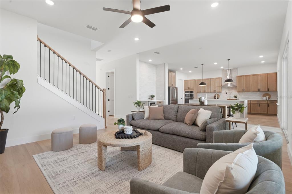 A bright open-concept living room features a grey sofa, armchairs, and a staircase with railings — 1907 MAE STREET, ORLANDO, FL