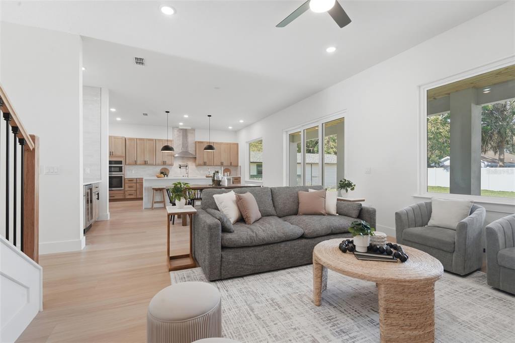 A bright open-concept living room features light wood floors, a gray sofa, and a kitchen — 1907 MAE STREET, ORLANDO, FL