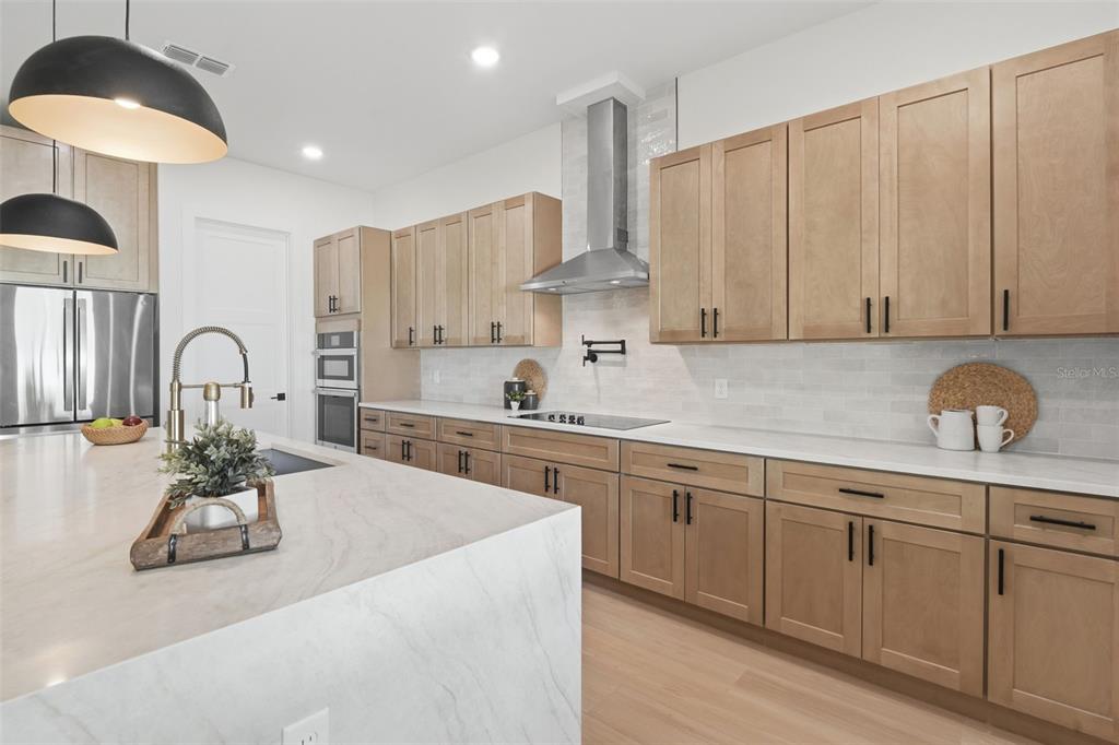 A modern kitchen features light wood cabinets, white countertops, and a large marble-topped island — 1907 MAE STREET, ORLANDO, FL