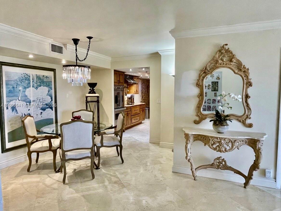 A dining area with a glass table and chandelier leads into a wooden kitchen — 1121 Crandon Blvd # D903, Key Biscayne FL 33149, KEY BISCAYNE, FL