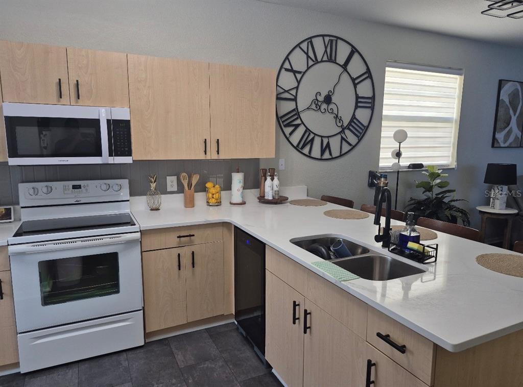 A kitchen features light wood cabinets, white countertops, a white oven, and a large wall clock — 6102 LAKE MARION GOLF RESORT, KISSIMMEE, FL