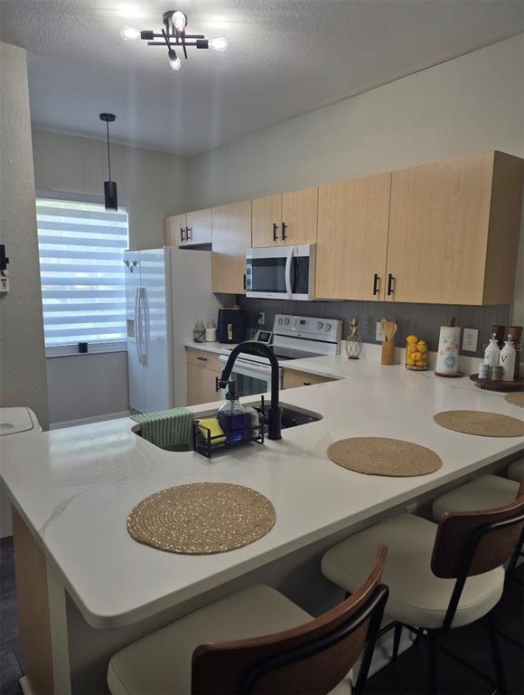 A kitchen features light wood cabinets, white countertops, a breakfast bar, and stainless steel appliances — 6102 LAKE MARION GOLF RESORT, KISSIMMEE, FL