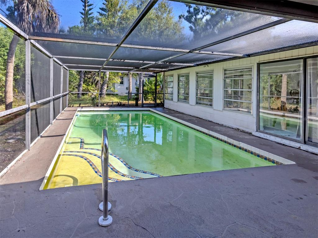 A screened-in swimming pool with a concrete deck sits beside a house with sliding doors — 3180 FALLOW ROAD, VENICE, FL
