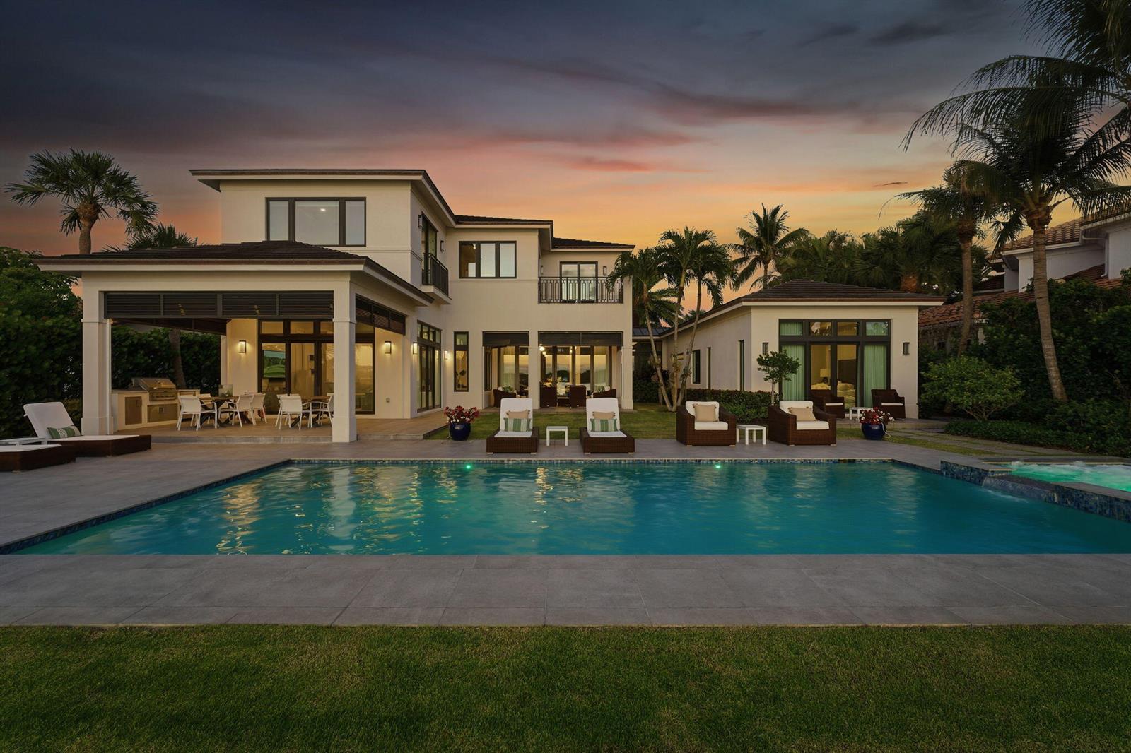 A two-story house with a swimming pool, patio, and palm trees at sunset — 825 W Oyster Lane, Lantana FL 33462, LANTANA, FL