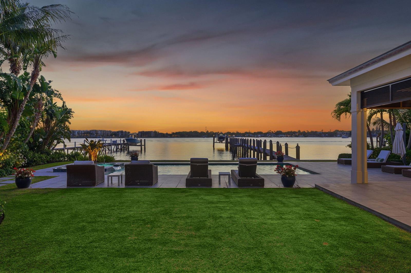 A backyard with a pool, lounge chairs, and a wooden dock overlooking a calm bay — 825 W Oyster Lane, Lantana FL 33462, LANTANA, FL