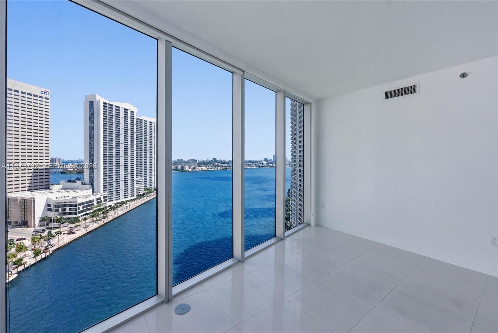 An empty room with white tile floors and floor-to-ceiling windows overlooking a bay and city — 465 Brickell Ave # 2002, Miami FL 33131, MIAMI, FL