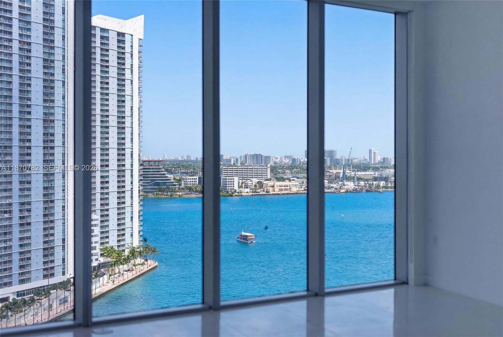 A view of a bay and city skyline through floor-to-ceiling windows in a room — 465 Brickell Ave # 2002, Miami FL 33131, MIAMI, FL
