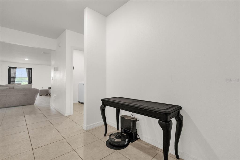 A black console table with a robotic vacuum sits against a white wall in a hallway — 123 ZINNIA LANE W, POINCIANA, FL