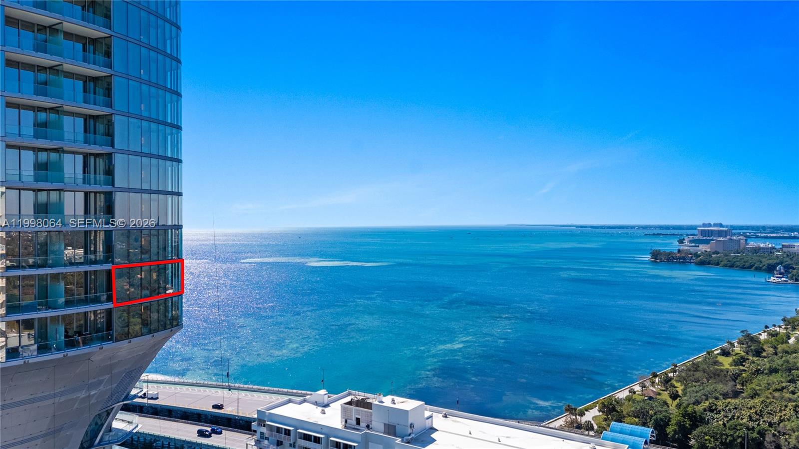 An exterior view of a glass high-rise building overlooking the ocean and a coastal road — 175 SE 25 Rd # 2003, Miami FL 33129, MIAMI, FL