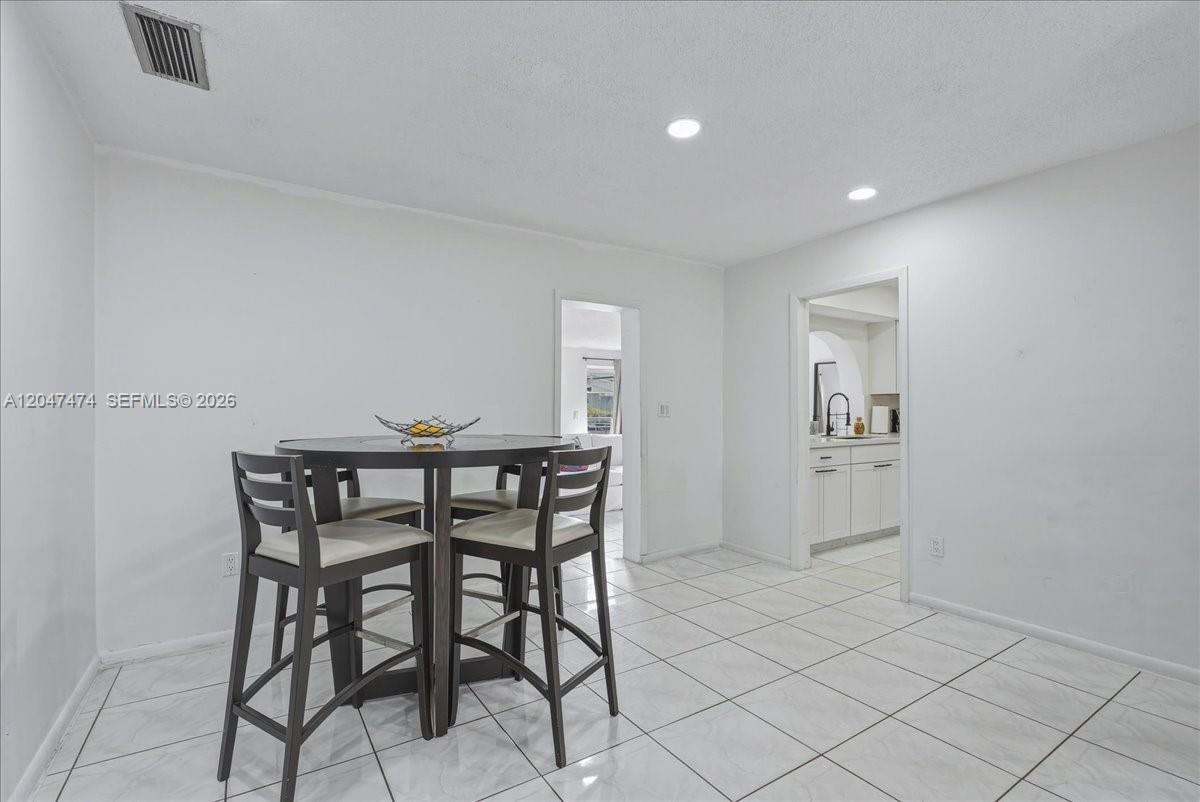 A dining area features a round table with four chairs and white tile flooring — 7850 W 16th Ave, Hialeah FL 33014, HIALEAH, FL