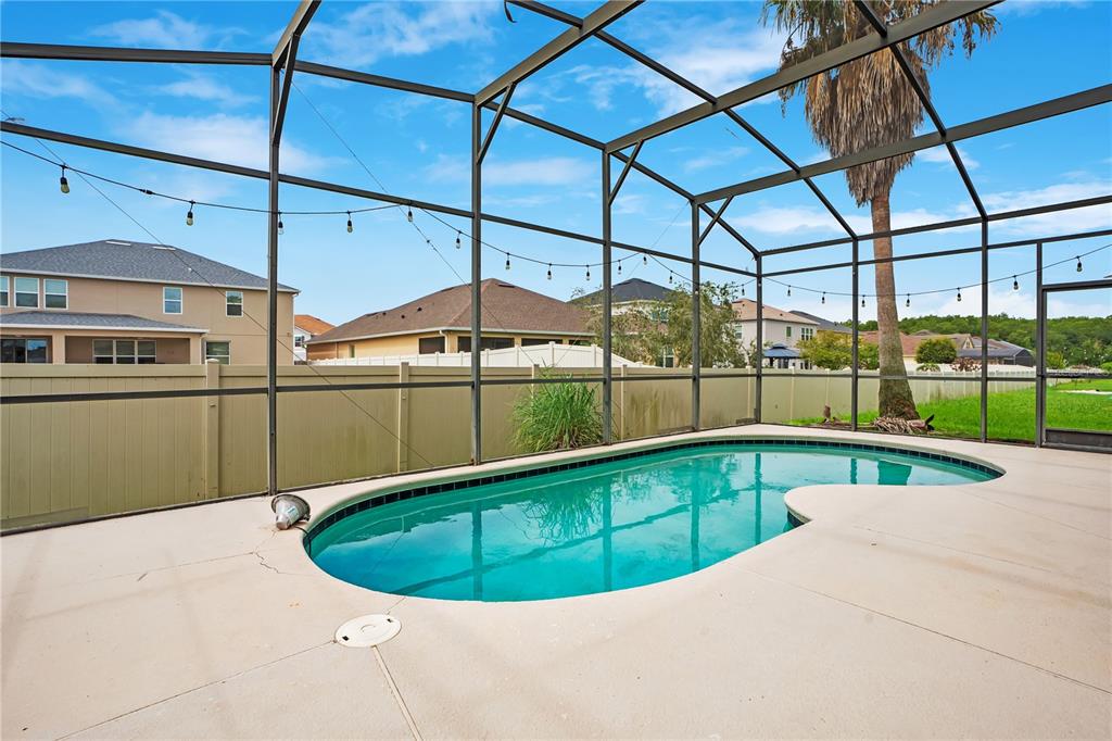 A swimming pool sits inside a screened-in patio enclosure with a beige concrete deck — 3571 MAPLE RIDGE LOOP, KISSIMMEE, FL