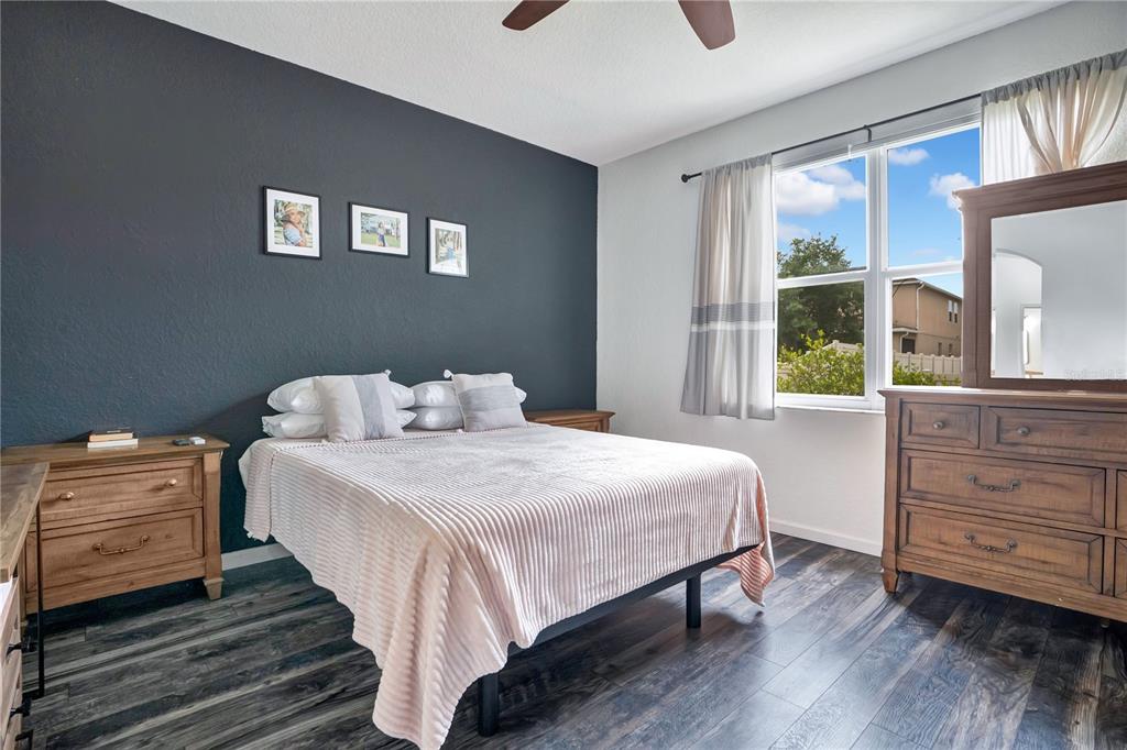 A bedroom features a dark accent wall, a bed with a light quilt, and wood furniture — 3571 MAPLE RIDGE LOOP, KISSIMMEE, FL