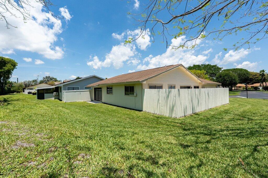 A light-colored house with a fenced backyard and a large grassy lawn under a blue sky — 1 Afton Place, Boynton Beach FL 33426, BOYNTON BEACH, FL