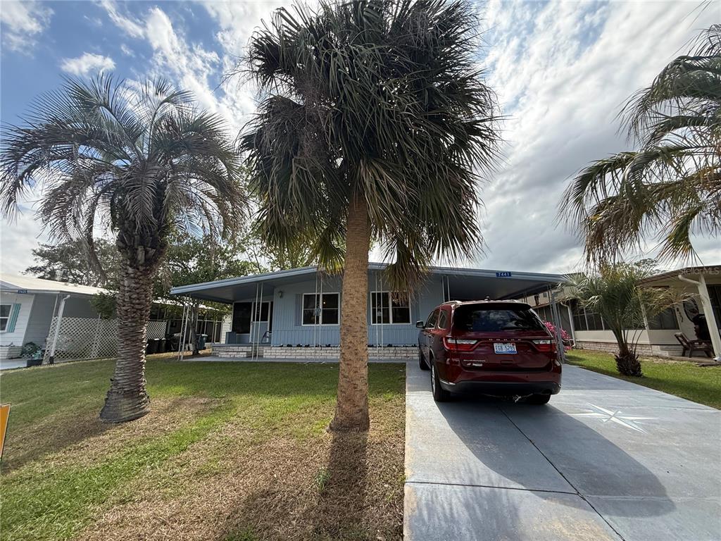 A light blue single-story house with a palm tree in the front yard and driveway — 7441 FAIRLANE AVENUE, BROOKSVILLE, FL