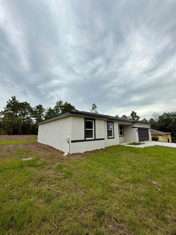 A single-story house with a light-colored stucco exterior, dark trim, and an attached garage — 11128 N G MARTINELLI BOULEVARD, CITRUS SPRINGS, FL