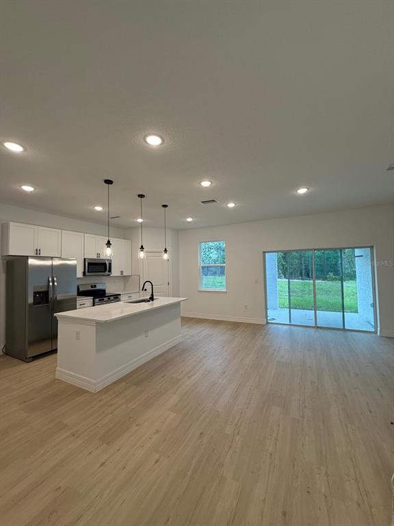A kitchen with white cabinets and a center island opens to a living area — 11128 N G MARTINELLI BOULEVARD, CITRUS SPRINGS, FL