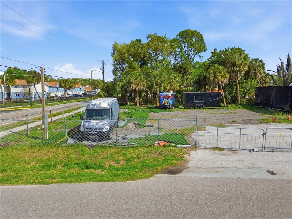 A fenced, gravel-covered vacant lot features a parked van and two storage containers — 7511 WINCHESTER DRIVE, TAMPA, FL