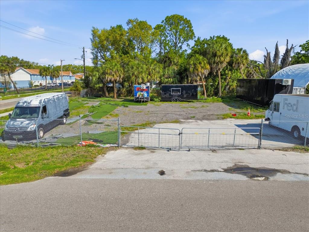 An outdoor fenced lot features a gravel surface, two trailers, and two parked vehicles — 7511 WINCHESTER DRIVE, TAMPA, FL