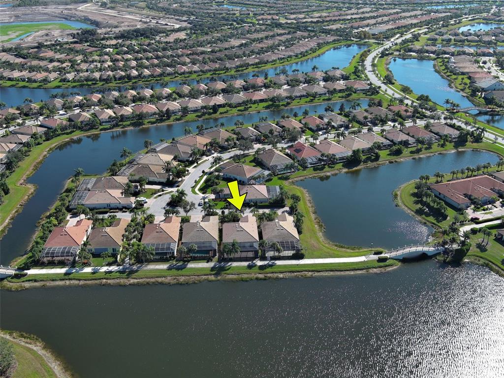 An aerial view shows a residential neighborhood with houses surrounding a large lake — 19267 KIRELLA STREET, VENICE, FL