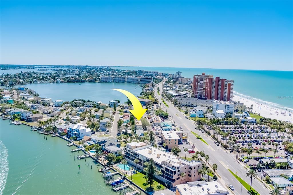 An aerial view shows a coastal neighborhood with a yellow arrow pointing to a building — 18111 1ST STREET E, REDINGTON SHORES, FL