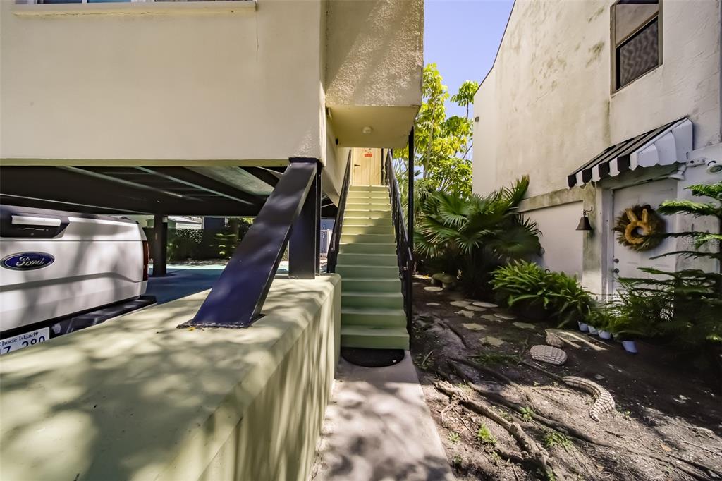 An exterior view shows a staircase leading to an elevated building entrance beside a carport — 18111 1ST STREET E, REDINGTON SHORES, FL