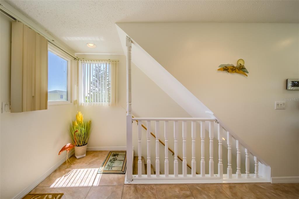 A staircase with a white railing sits next to a window and tiled floor — 18111 1ST STREET E, REDINGTON SHORES, FL