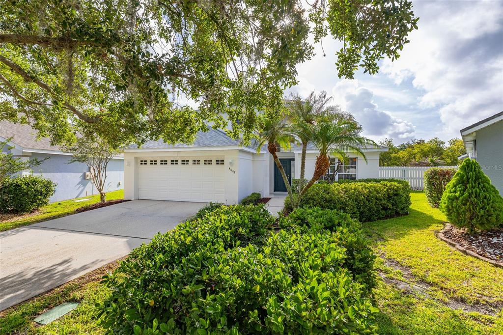 A white house with a two-car garage and landscaped front yard under a large tree — 4638 RAINTREE RIDGE ROAD, ORLANDO, FL
