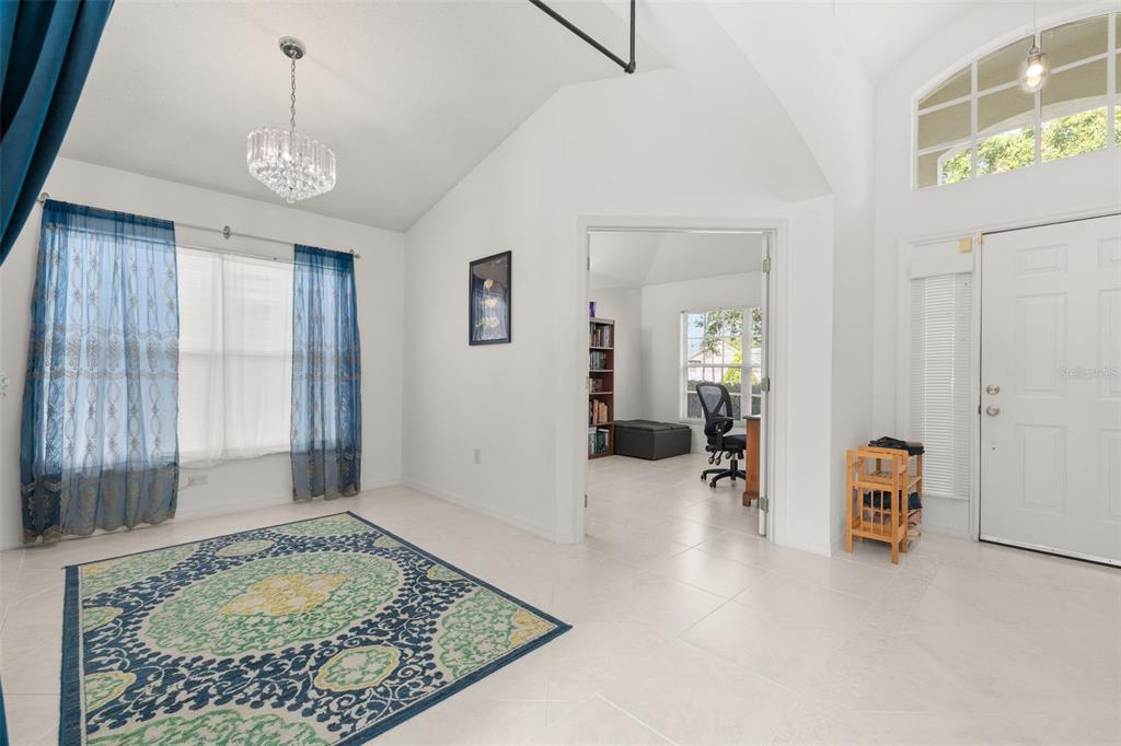 A bright room with white tile floors, a patterned rug, and a doorway to an office — 4638 RAINTREE RIDGE ROAD, ORLANDO, FL