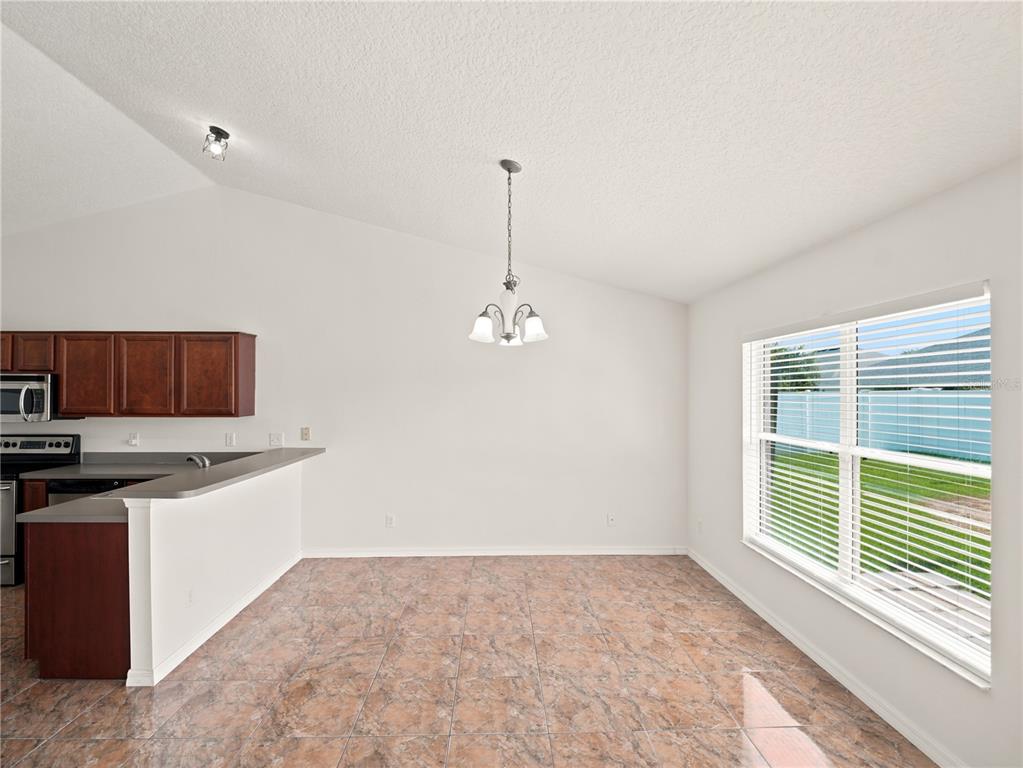 A dining area with tile flooring, a hanging light fixture, and a window overlooking a yard — 6013 BRICK ROAD, ST CLOUD, FL