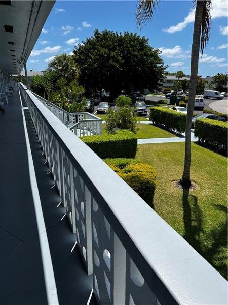A view from an elevated balcony overlooking a parking lot, green lawn, and palm tree — 701 Pine Drive # 204, Pompano Beach FL 33060, POMPANO BEACH, FL