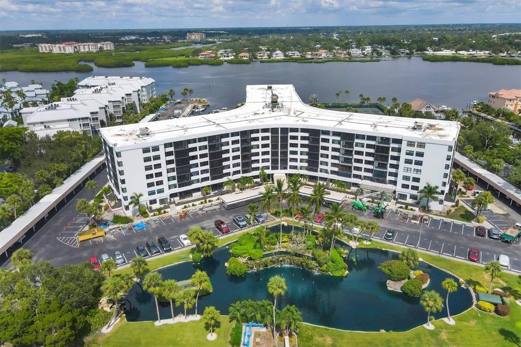 An aerial view shows a large, Y-shaped apartment building with a pond and parking lot — 5855 MIDNIGHT PASS ROAD UNIT 420, SARASOTA, FL