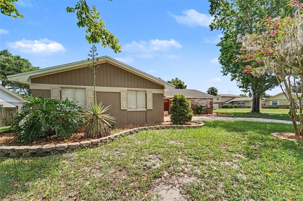 A single-story house with brown siding and a stone-bordered garden bed in the front yard — 930 OAK FOREST DRIVE, WINTER SPRINGS, FL